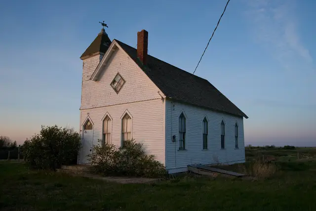 Old white wooden church on the prairie at dusk